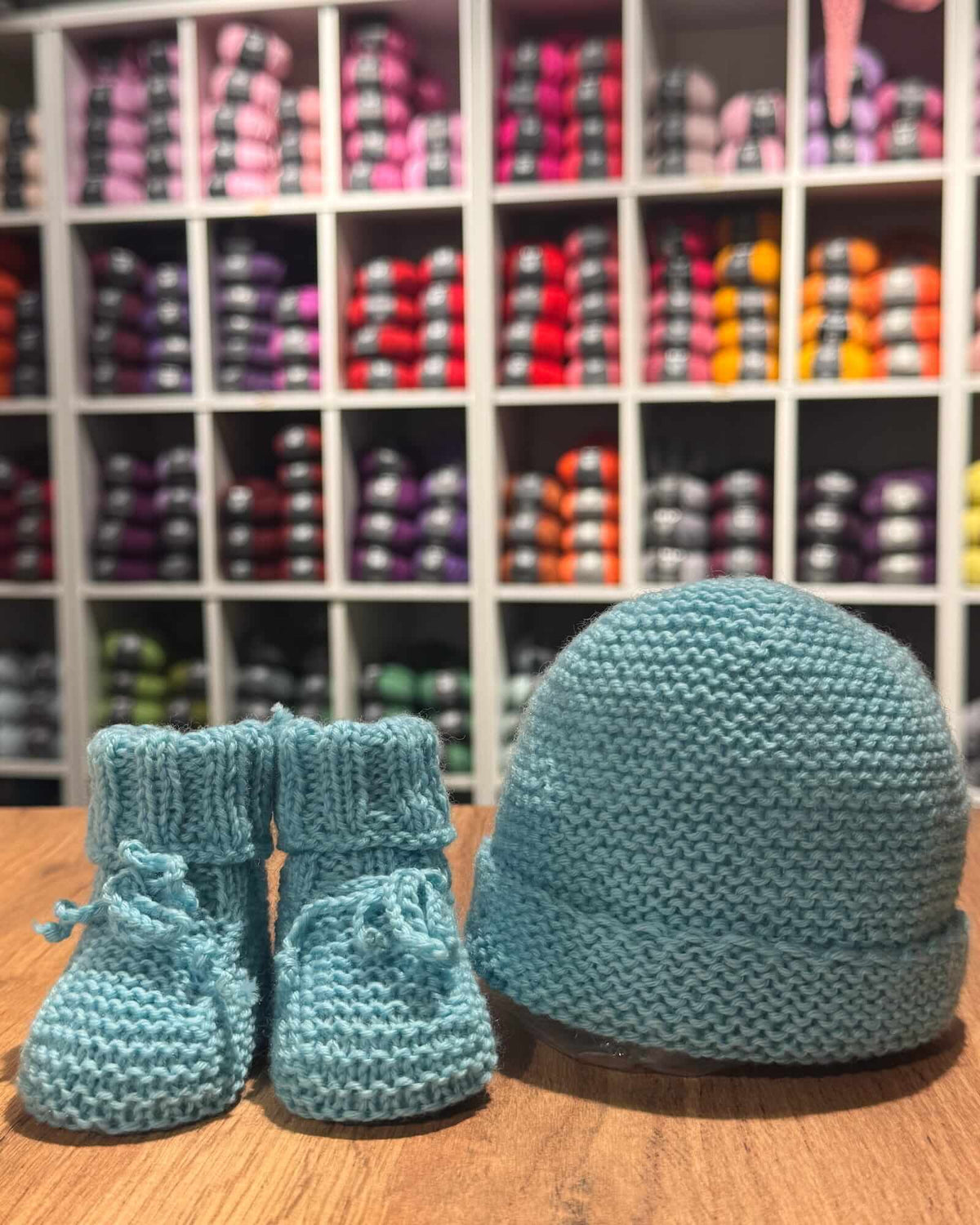 Hand-knitted dusty teal baby hat and matching booties set made from 100% merino wool